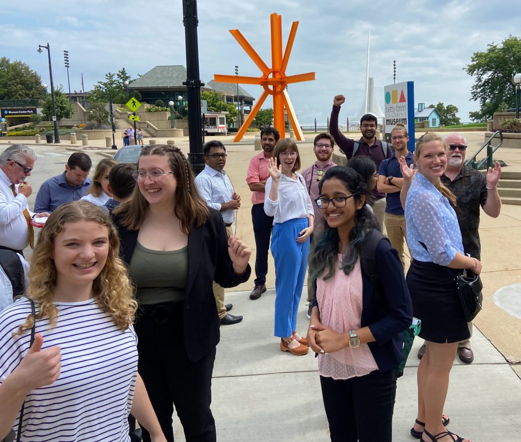 Students wave and smile outside of a museum on the 2023 Milwaukee trip.