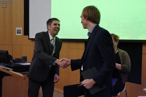 Two men shake hands.