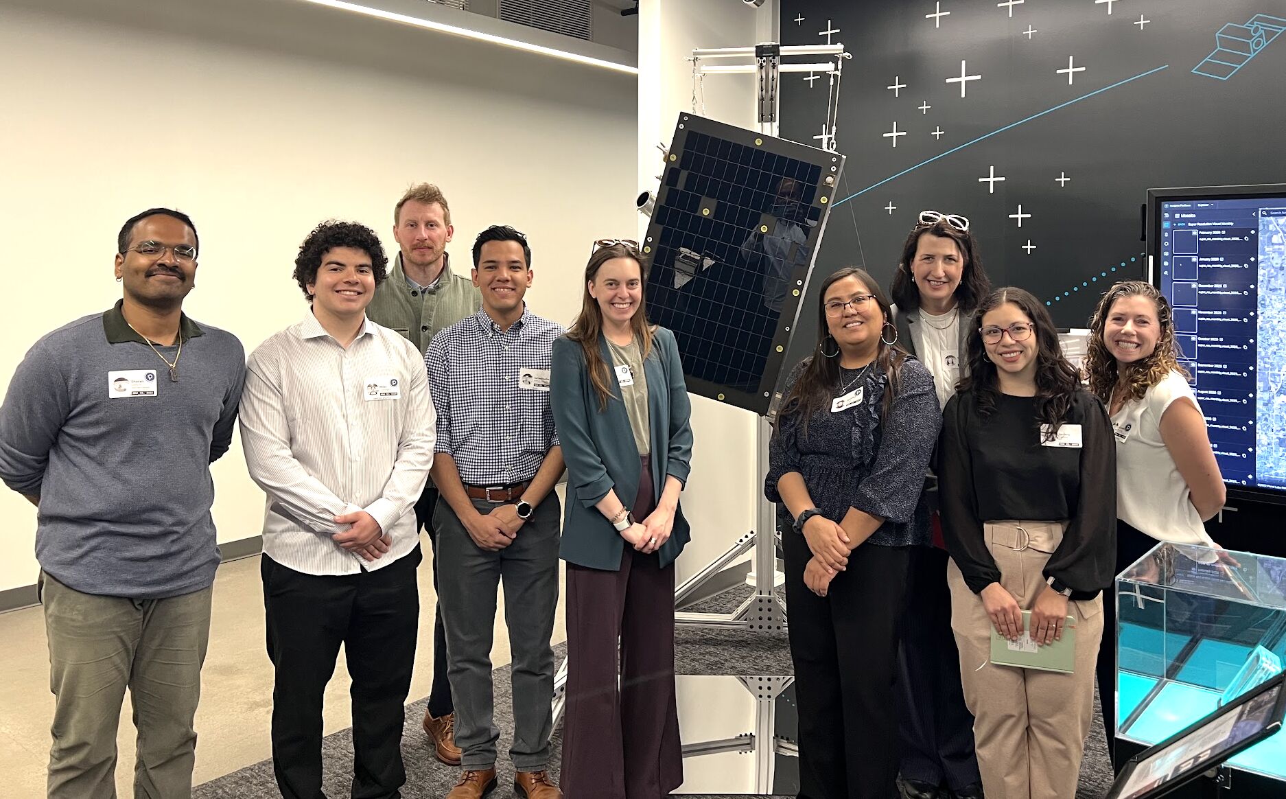 Students and faculty pose near a solar panel